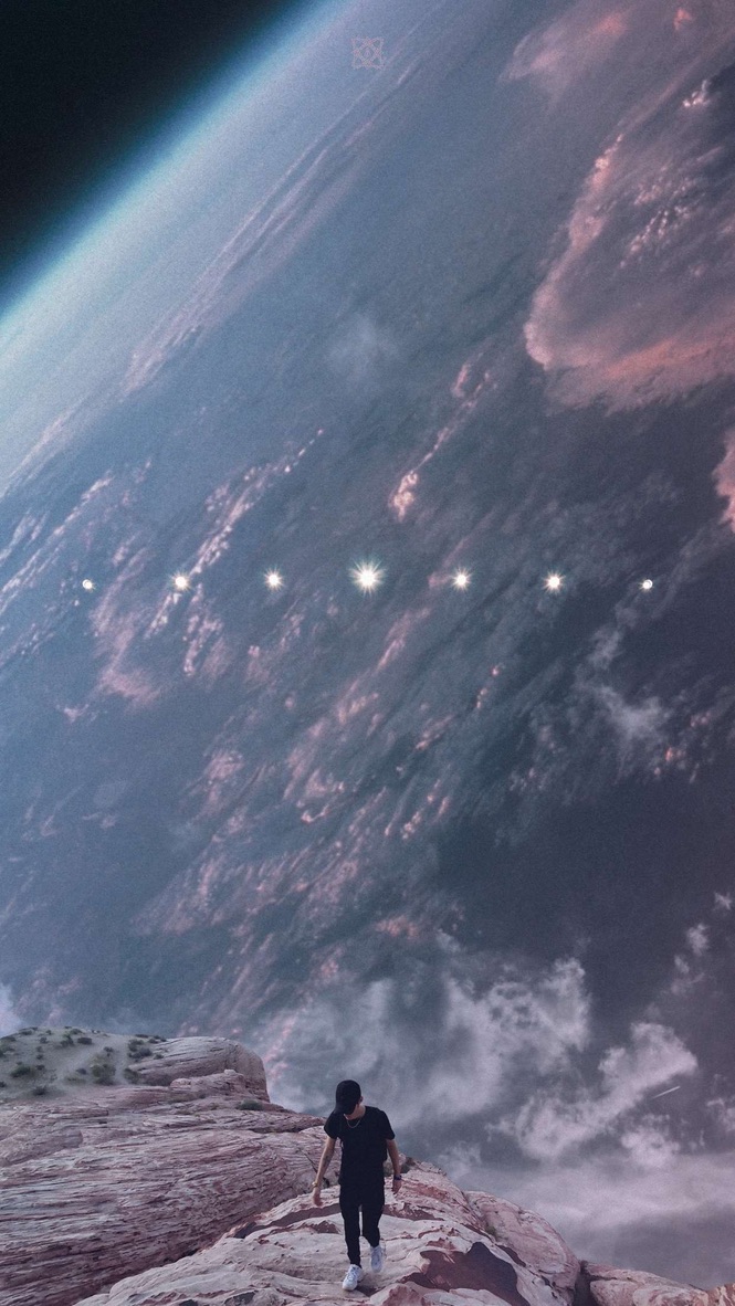 Figure walking on a ridge beneath a vast planet in orbit