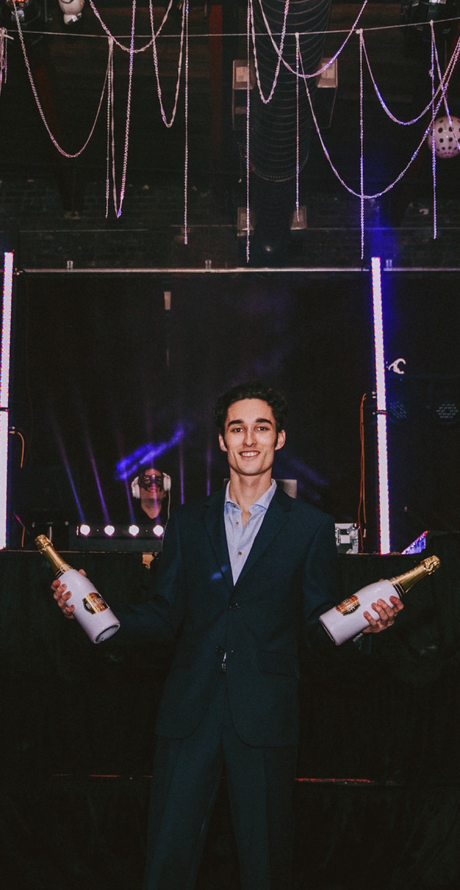 Christian Holman in a tuxedo holding champagne bottles at the Masquerade Ball